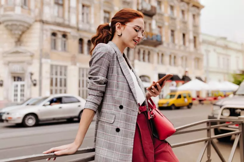 Blazer xadrez de rua de mulher na moda verificando telefone