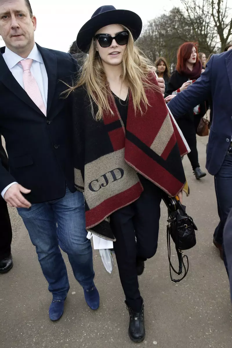 Cara Delevingne memakai poncho monogram Burberry di London. Foto: FilmMagic