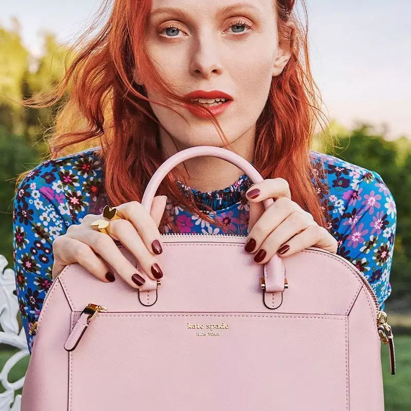 Modelo Karen Elson pozas kun rozkolora sako en la kampanjo printempo-somera 2020 de Kate Spade