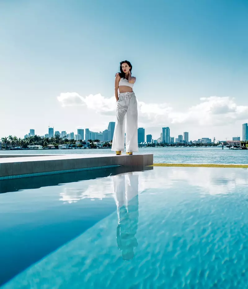 Posando junto a la piscina, Adriana Lima viste una camiseta recortada, pantalones y cinturón Sportmax