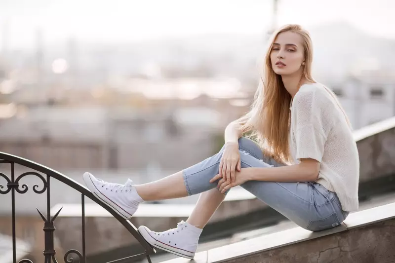 Modèle blonde avec un haut en tricot, un jean et des baskets blanches