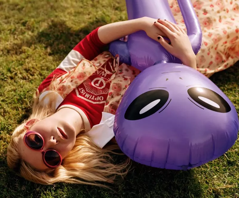 Elle Fanning pózuje na trávě a drží fialovou mimozemskou hračku