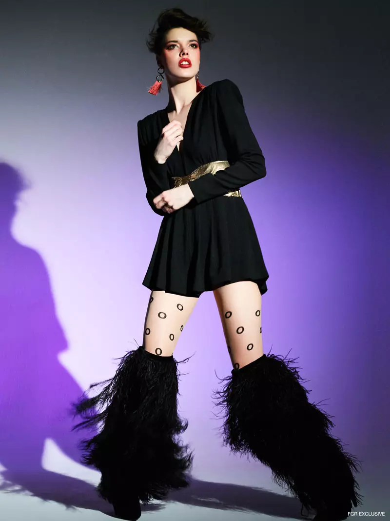 Saint Laurent speelpak met goue strik- en volstruisveer en fluweelstewel, Wolford Miley ondeursigtige deurskynende tights en The2Bandits geometriese tosseloorbelle. Foto: Enrique Vega