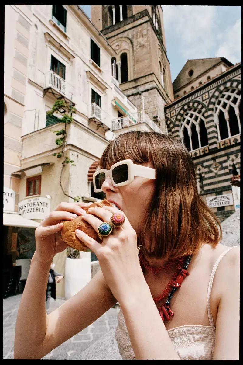 La modella mangia un hamburger con gli occhiali da sole alla moda di Zara.