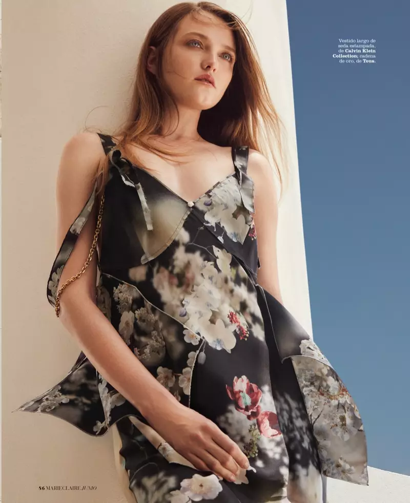 Blonďatá modelka má na sobě saténové slipové šaty s květinovým potiskem z kolekce Calvin Klein