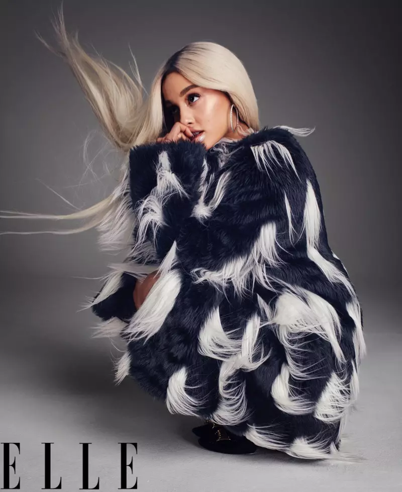 Kantistino Ariana Grande pozas en Givenchy finfelta mantelo, orelringoj Hearts On Fire kaj pumpiloj Louis Vuitton
