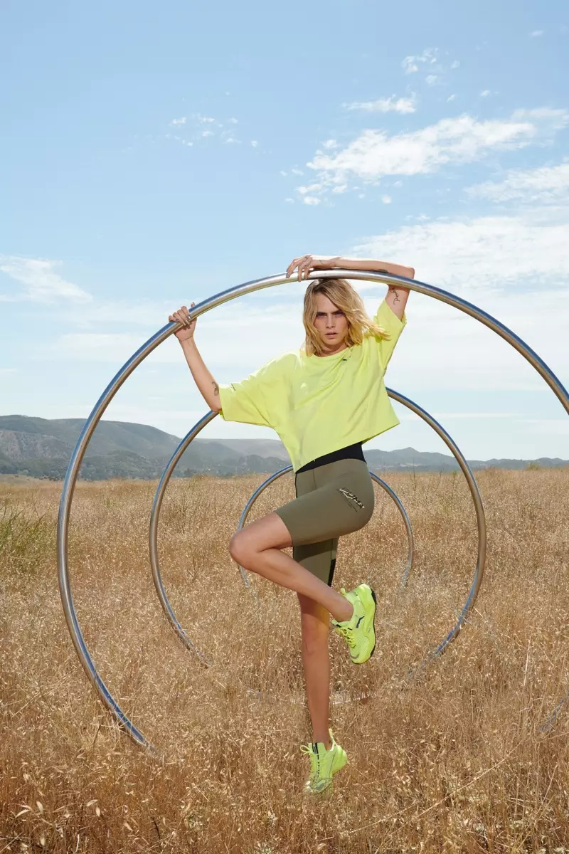 Gan sefyll yn yr awyr agored, mae Cara Delevingne yn arwain ymgyrch sneaker PUMA Rise Neon.