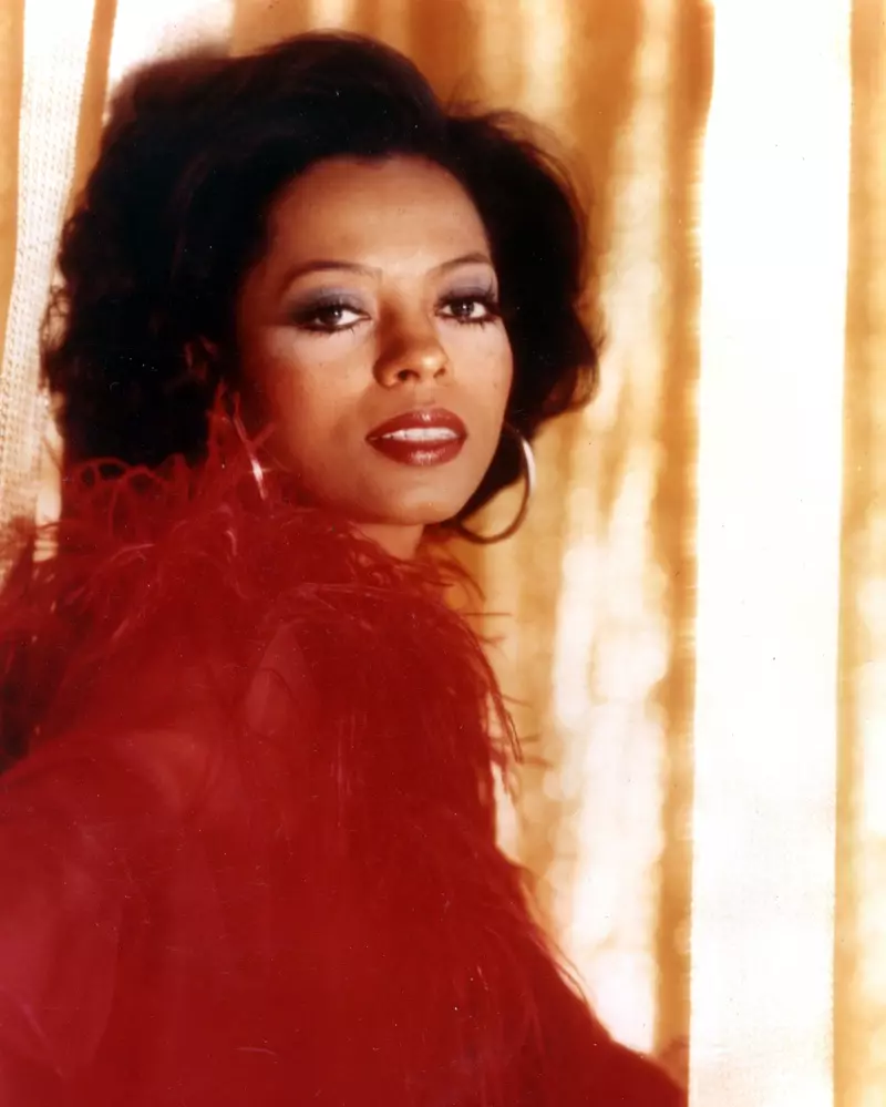 Diana Ross ក្នុងឆ្នាំ 1970 ពាក់ក្រវិល និងសំលៀកបំពាក់ពណ៌ក្រហម។ | ឥណទានរូបថត៖ Pictorial Press Ltd / Alamy Stock Photo