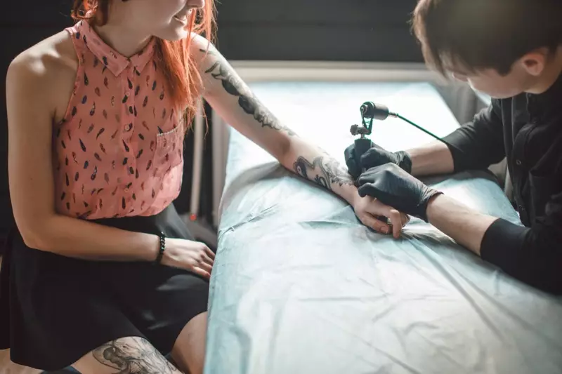 Donna che ottiene la seduta del tatuaggio