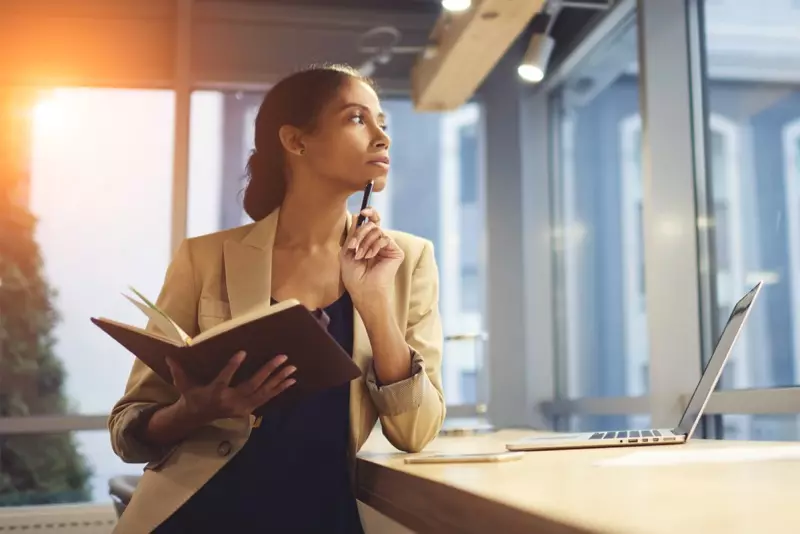 Dona negra sostenint un llibre de ploma escriptori pensatiu