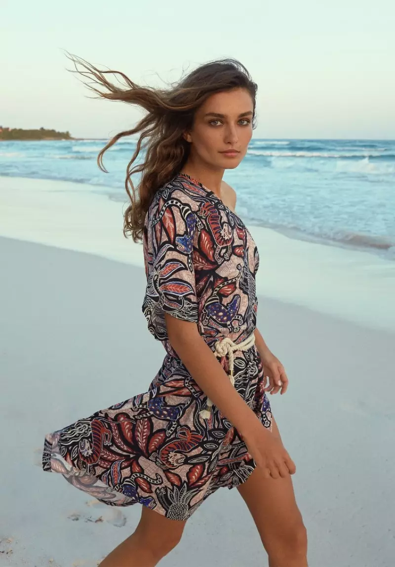 Andreea Diaconu, wat op die strand poseer, dra 'n gedrukte rok van H&M