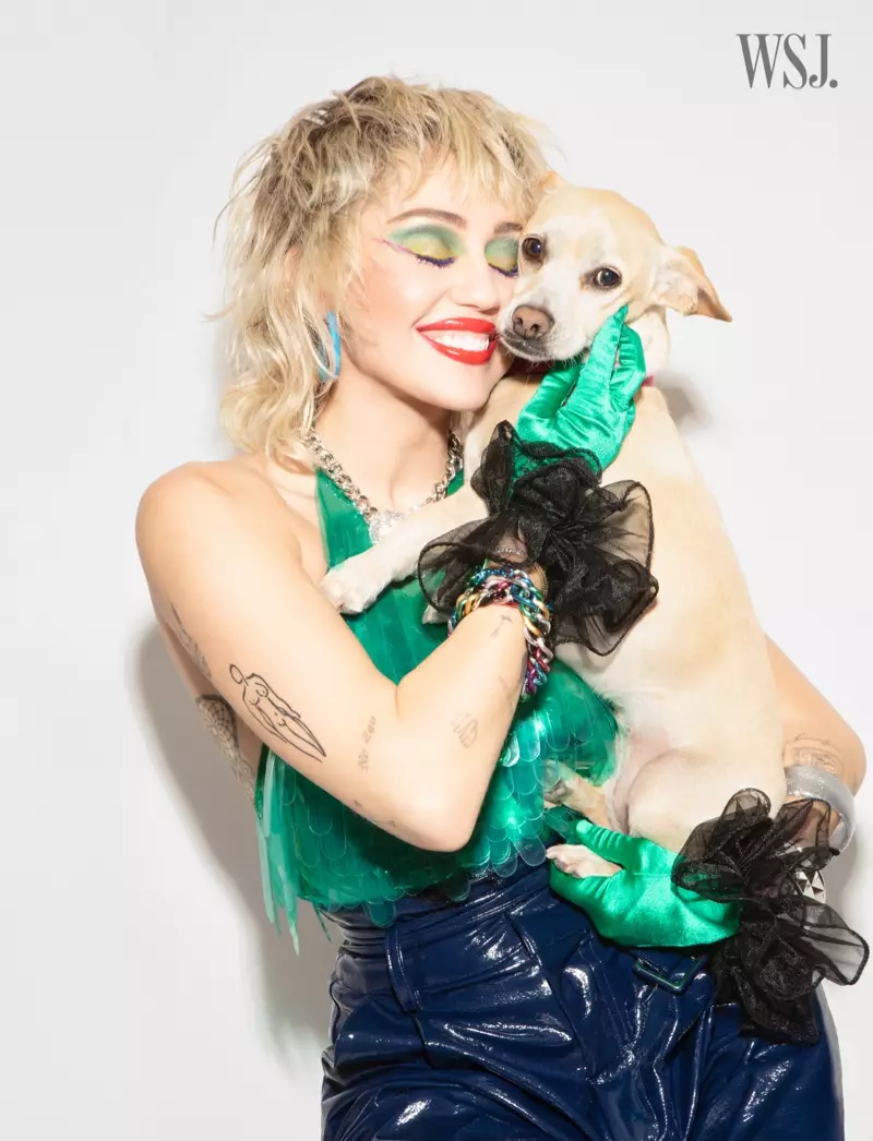 Miley Cyrus poserer sammen med hunden sin og smiler.