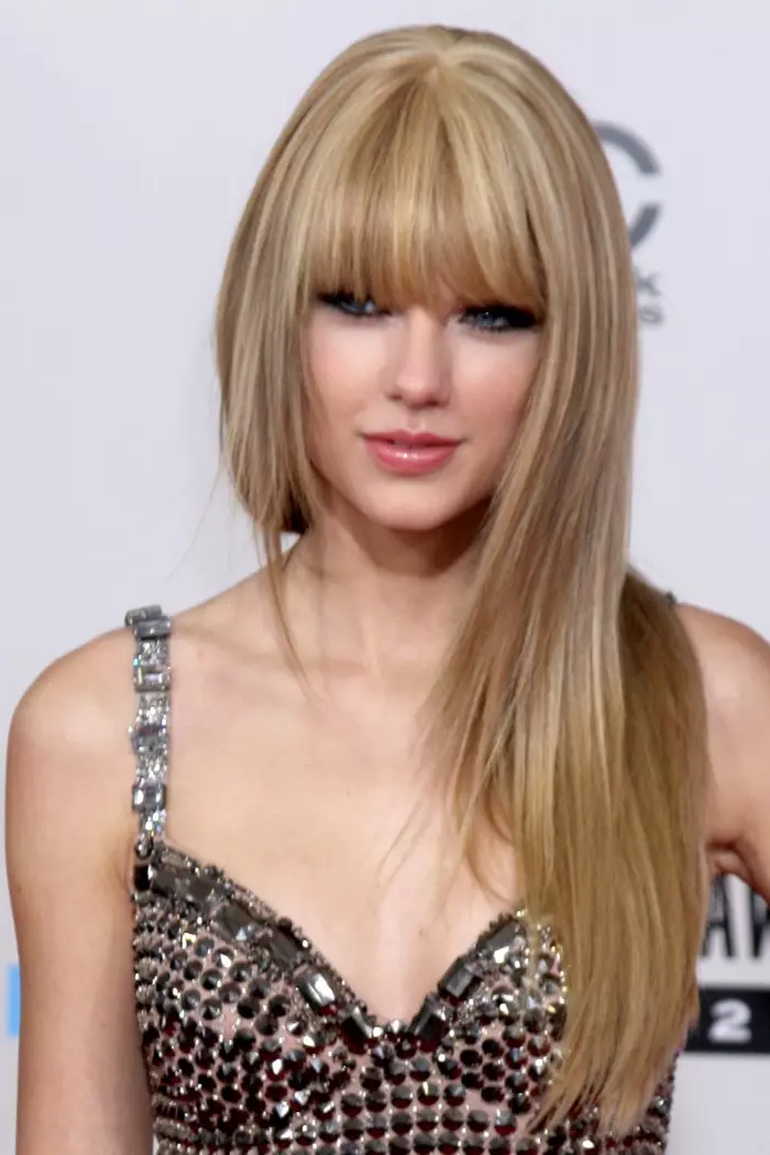 Ni ayika isubu ti 2010, Taylor debuted Blunt bangs. Nibi o wa bi Aami-ẹri Orin Amẹrika ti o wọ irun gigun ati titọ pẹlu omioto rẹ. Fọto: Helga Eseb / Shutterstock.com