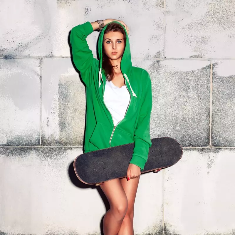 Mace a cikin Green Hoodie tare da Skateboard