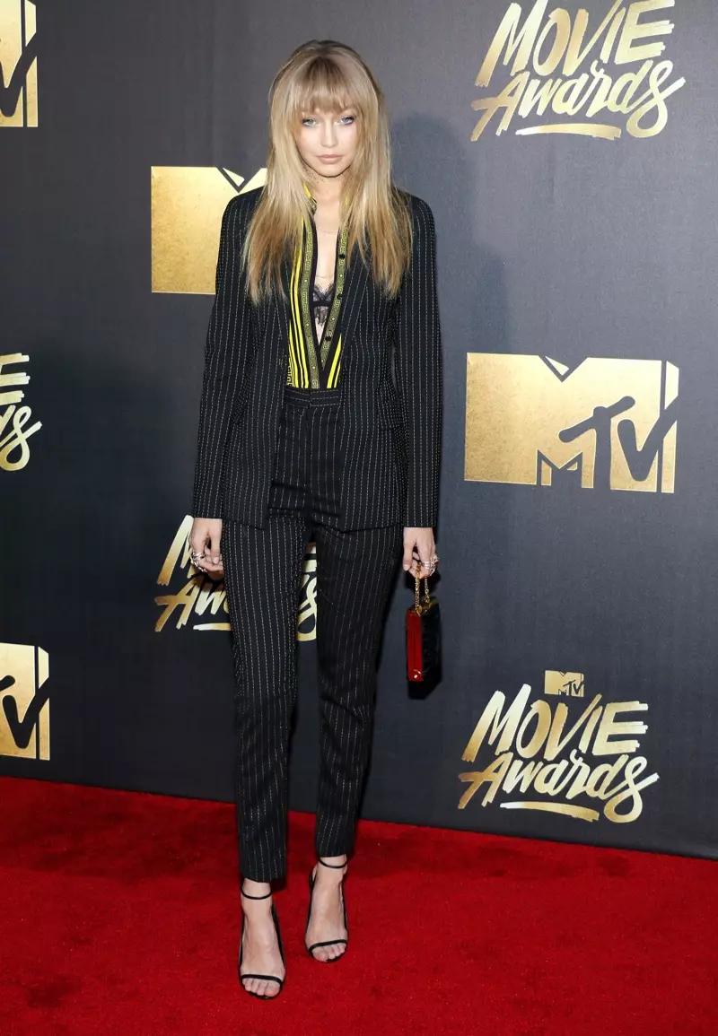 APRIL 2016: Gigi Hadid adagunda kapeti yofiyira pa MTV Movie Awards 2016 mu Versace top ndi mathalauza amizeremizere. Chithunzi: Tinseltown / Shutterstock.com