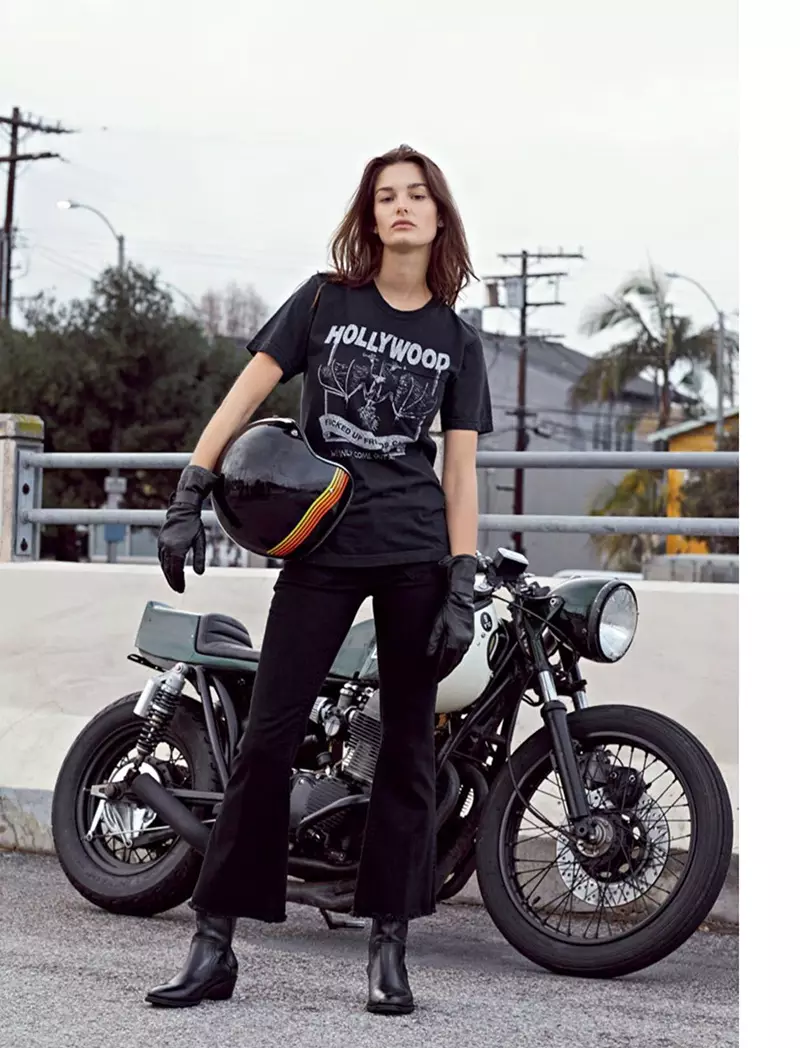 Ophelie Guillermand 在摩托车旁边摆姿势，身着 Local Authorities T 恤、Seafarer 牛仔裤和 Zadig & Voltaire 靴子