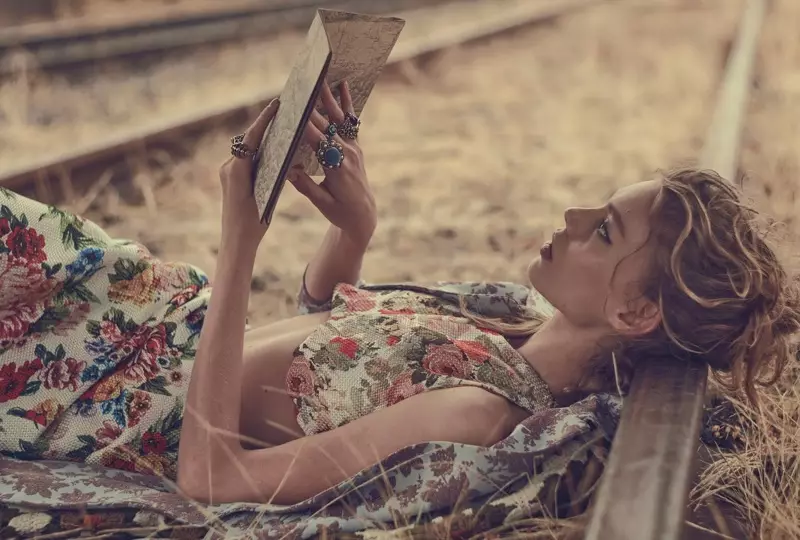 A modelo descansa em um top floral e saia enquanto lê um livro