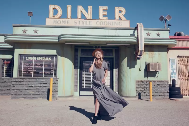 Nagpo-posing sa labas ng isang kainan, ang modelo ay nagsusuot ng kulay abong maxi dress mula sa Wildfox