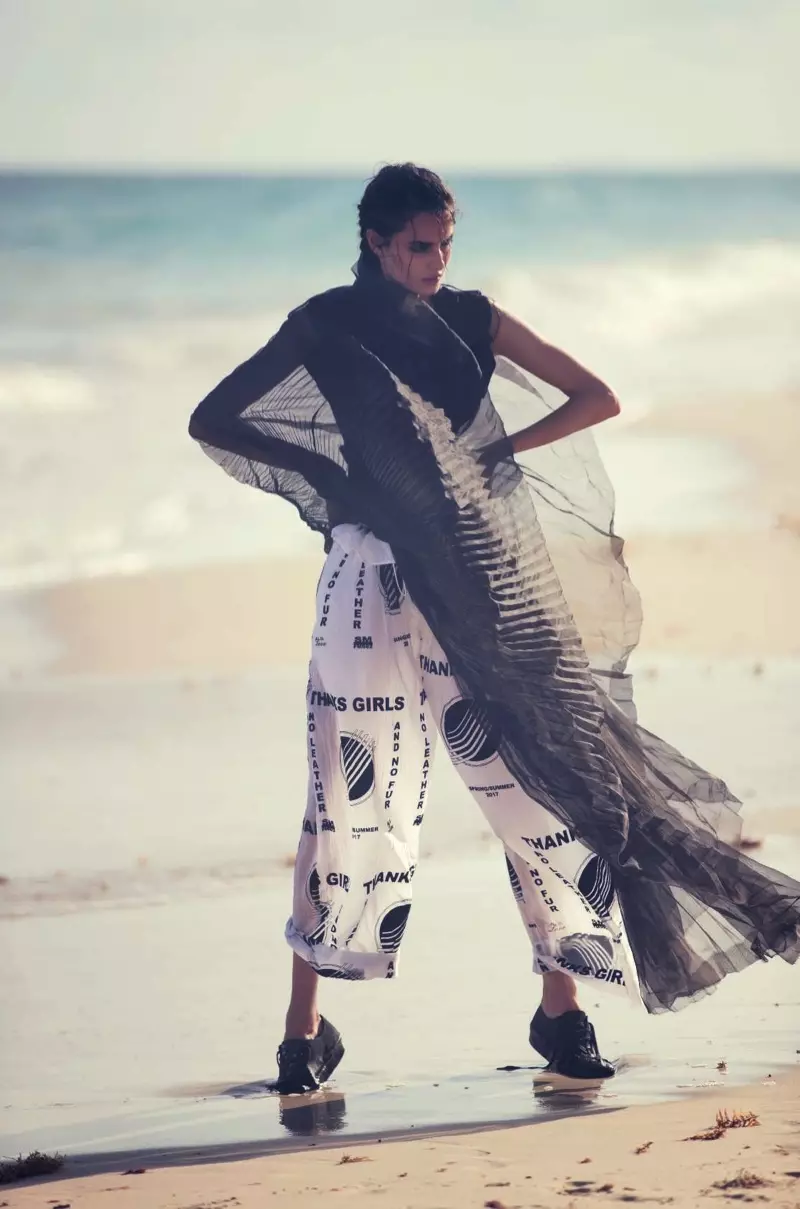 Paplūdimyje pozuojanti Blanca Padilla vilki Stella McCartney viršutinę dalį ir kelnes su Yohji Yamamoto sportbačiais