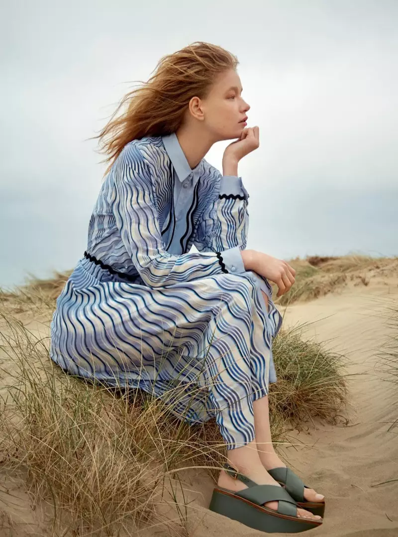 Het model poseert op het strand in een jurk met Mary Katrantzou-print