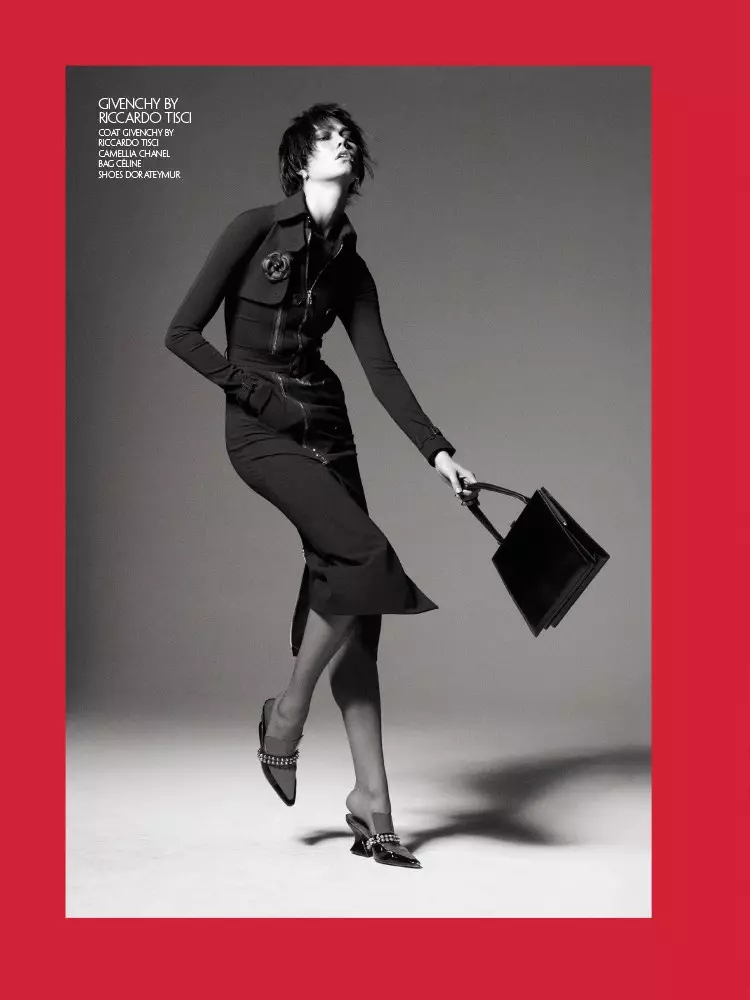 Fotografert i svart og hvitt, modellerte Karlie Kloss Givenchy-frakk, Chanel Camellia-brosje, Celine-veske og Dorateymur-sko