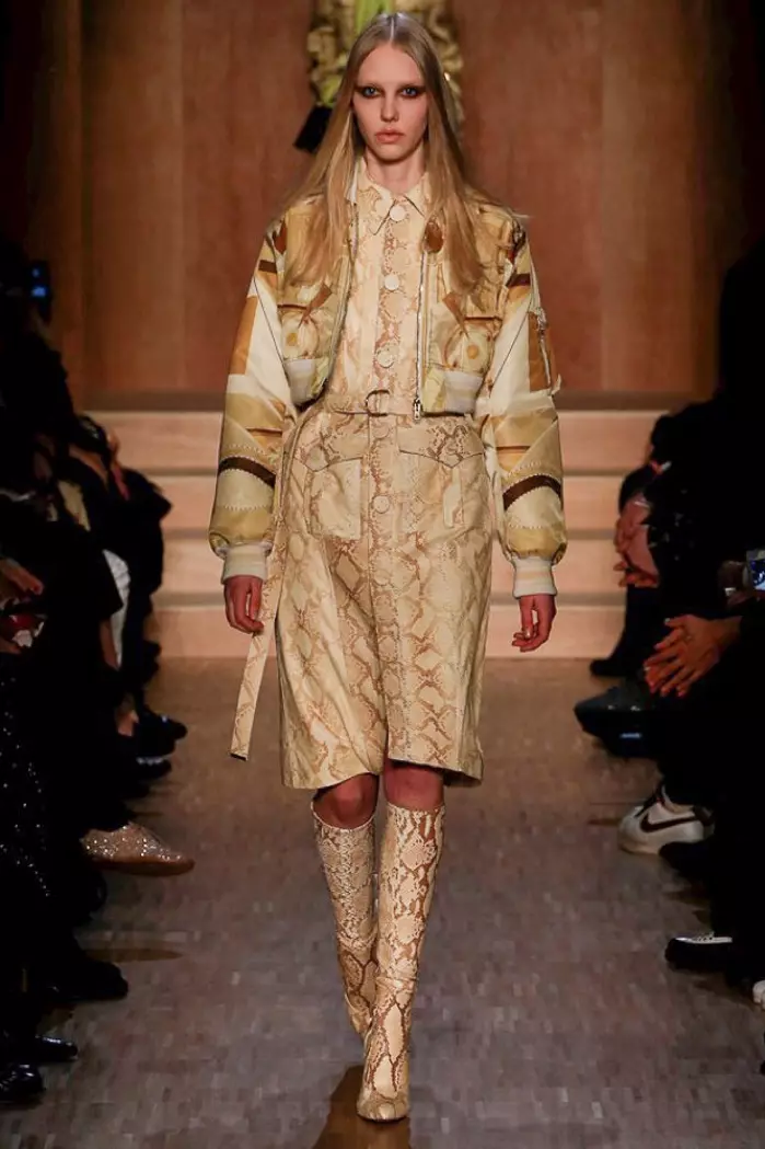 Unha modelo percorre a pasarela do desfile outono-inverno 2016 de Givenchy vestindo unha cazadora corta, un vestido estampado de pitón e botas ata os xeonllos