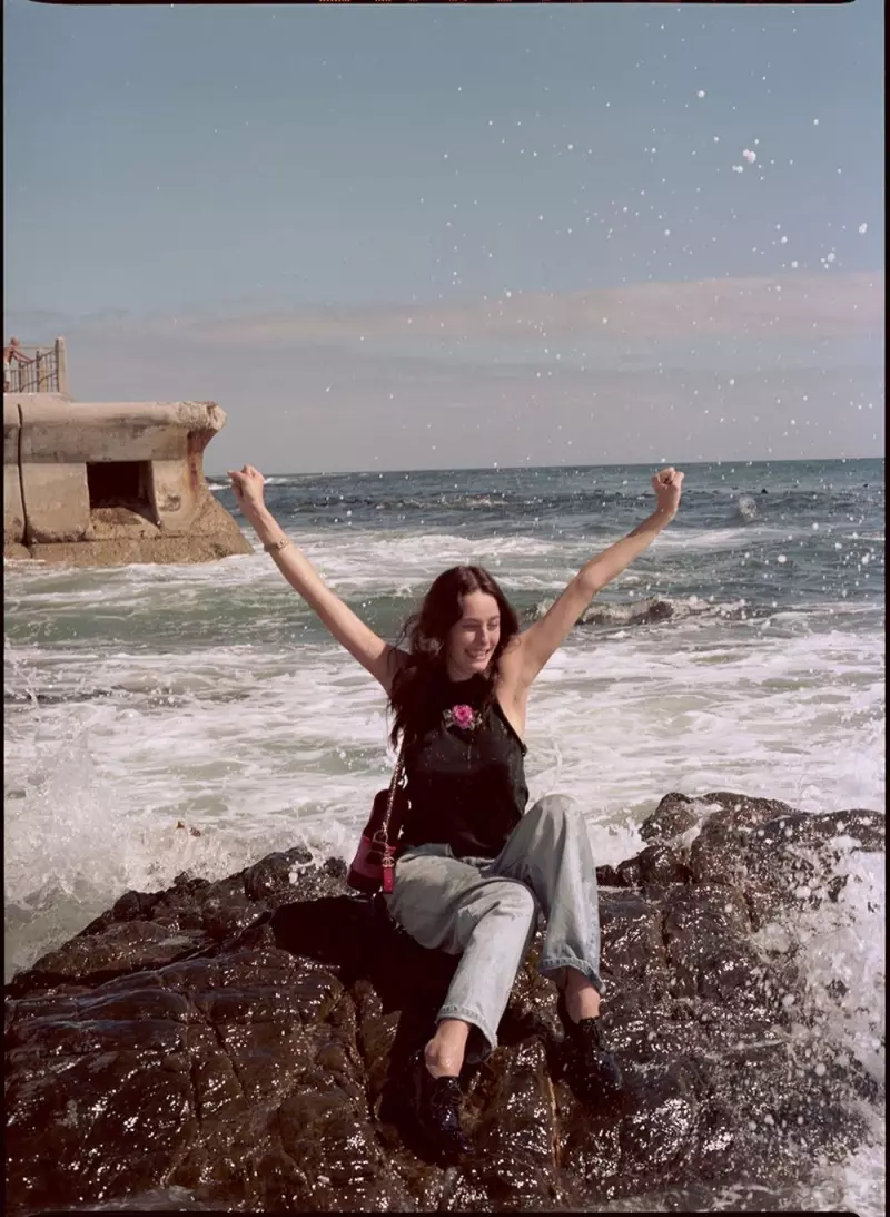 Kaya Scodelario poseert op het strand en draagt een geborduurde top en jeans