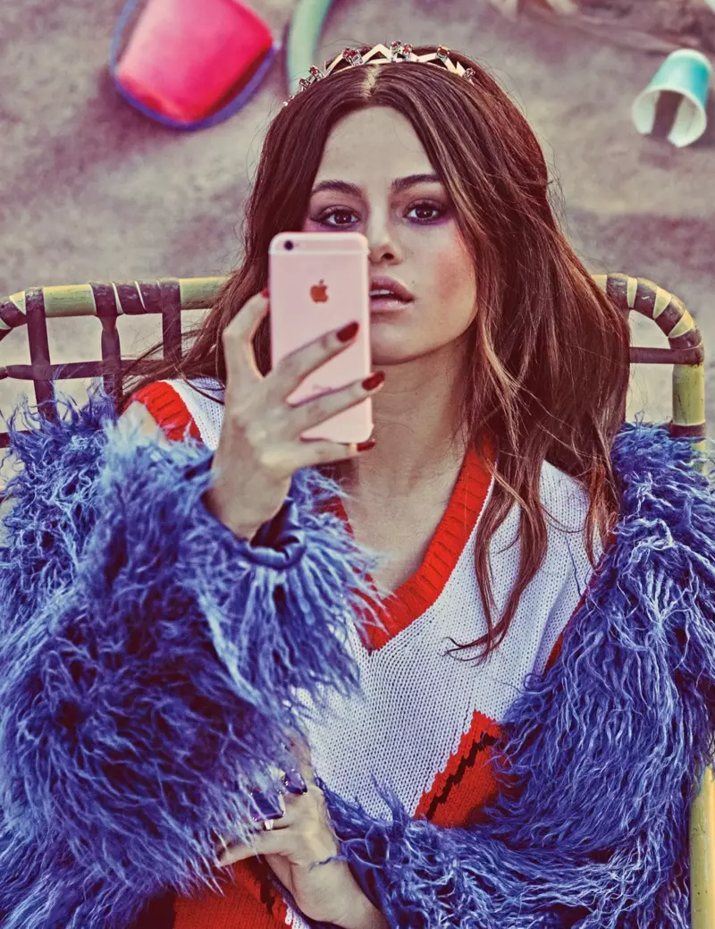 Selena Gomez bi kirasekî Topshop û êlekê şorpê Prada li iPhone-a xwe dinêre
