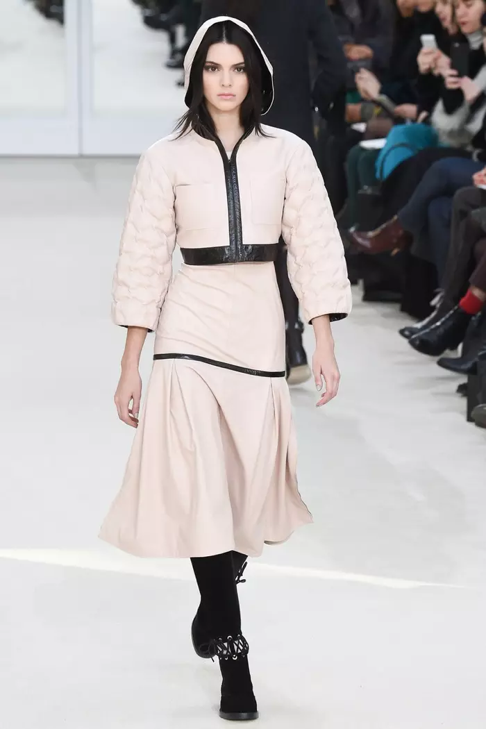 Kendall Jenner rin ni oju opopona ni ifihan Chanel's isubu-igba otutu 2016 ti o wọ jaketi hooded Pink ati yeri pẹlu gige alawọ.