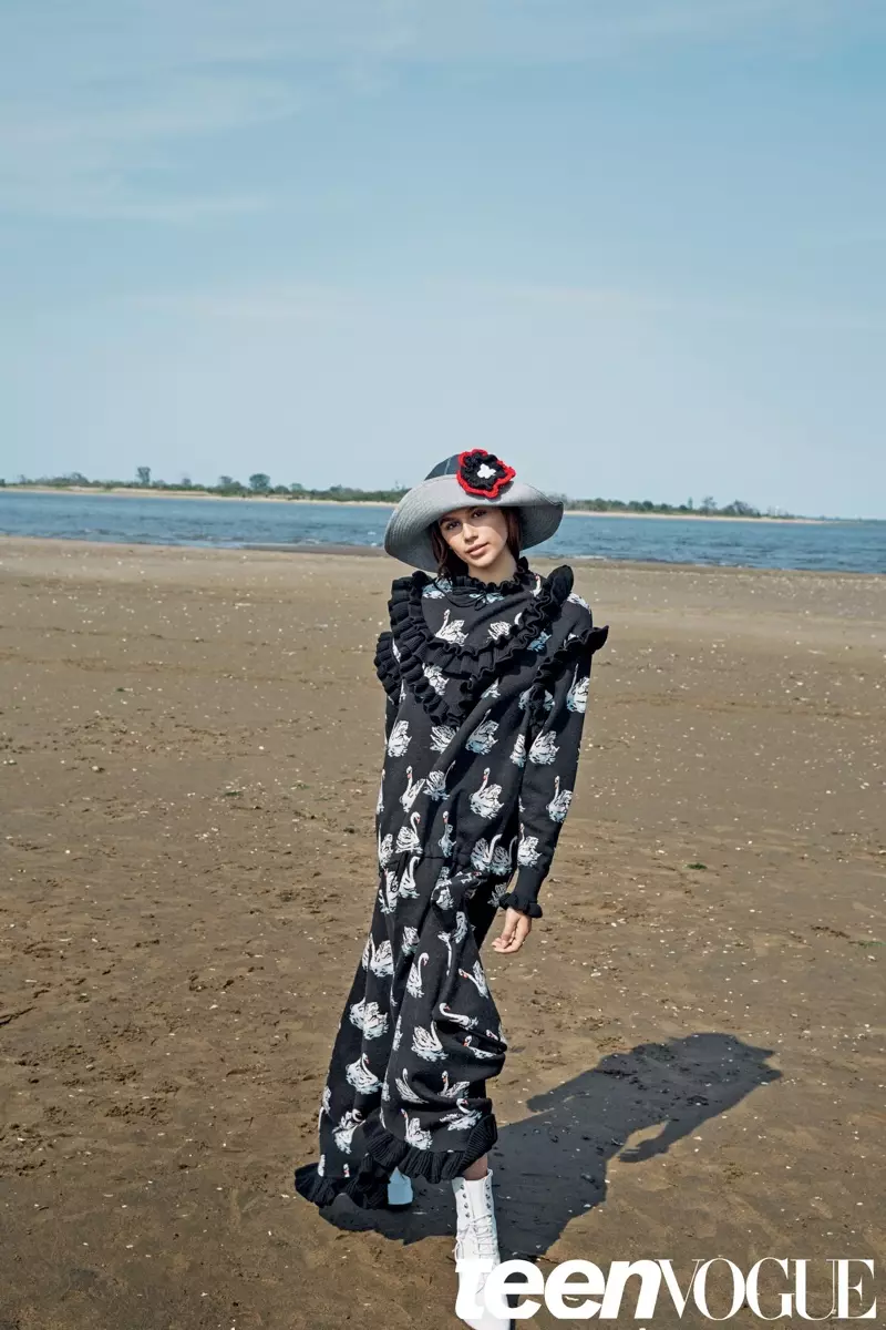 Kaia Gerber berpose di pantai mengenakan ruffle yang menghiasi gaun Stella McCartney dengan topi Lola Hats