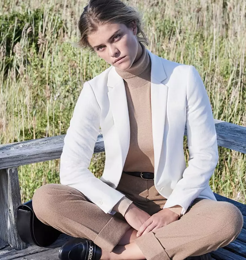 It model sjocht skerp yn in wite blazer mei in kamiel turtleneck en broek