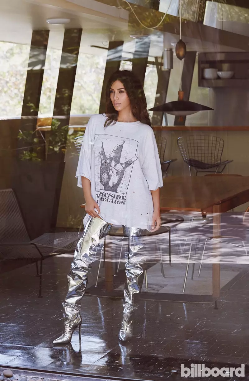 Kim Kardashian posearret yn oversized grafysk shirt en metalen laarzen