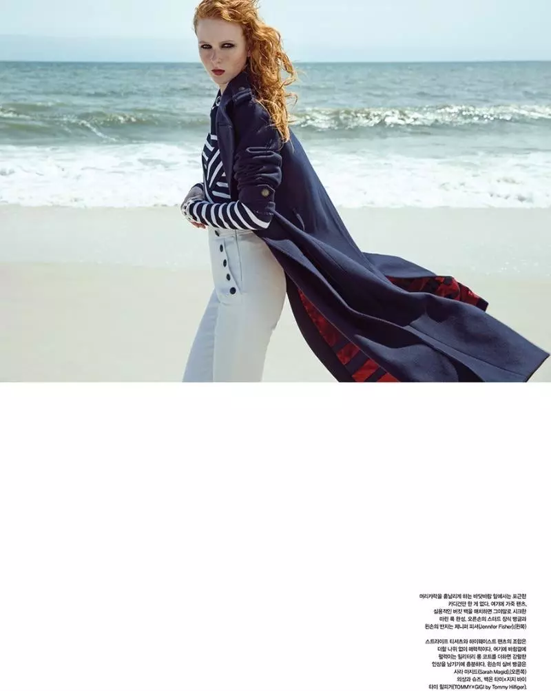 Χτυπώντας στην παραλία, η Madison Stubbington φοράει ναυτικό παλτό, ριγέ πουλόβερ και παντελόνι από την Gigi Hadid x Tommy Hilfiger