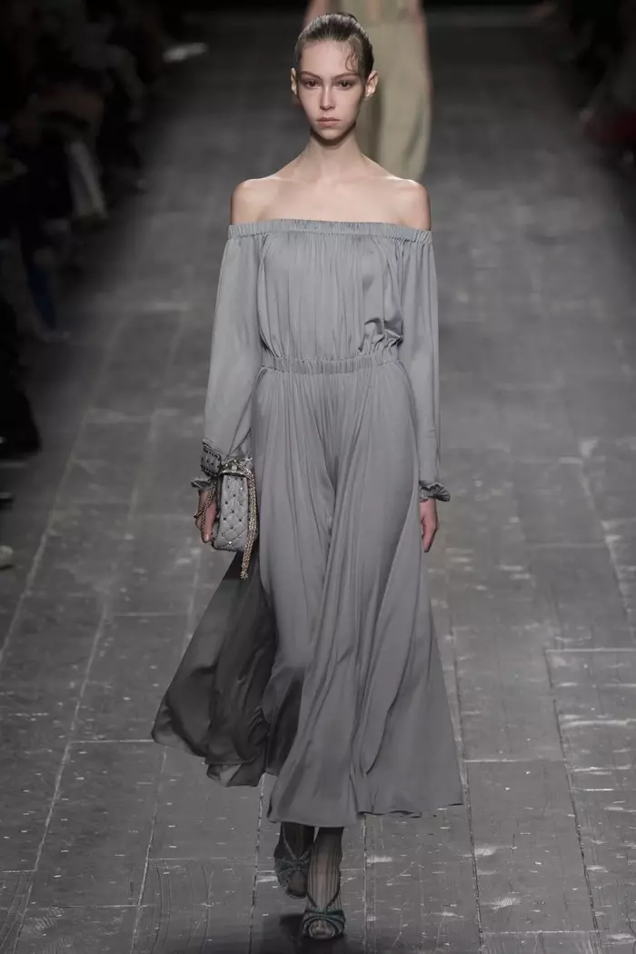 E Modell trëppelt d'Piste bei Valentino's Hierscht-Winter 2016 Show an huet en off-shoulder laang-sleeve Kleed