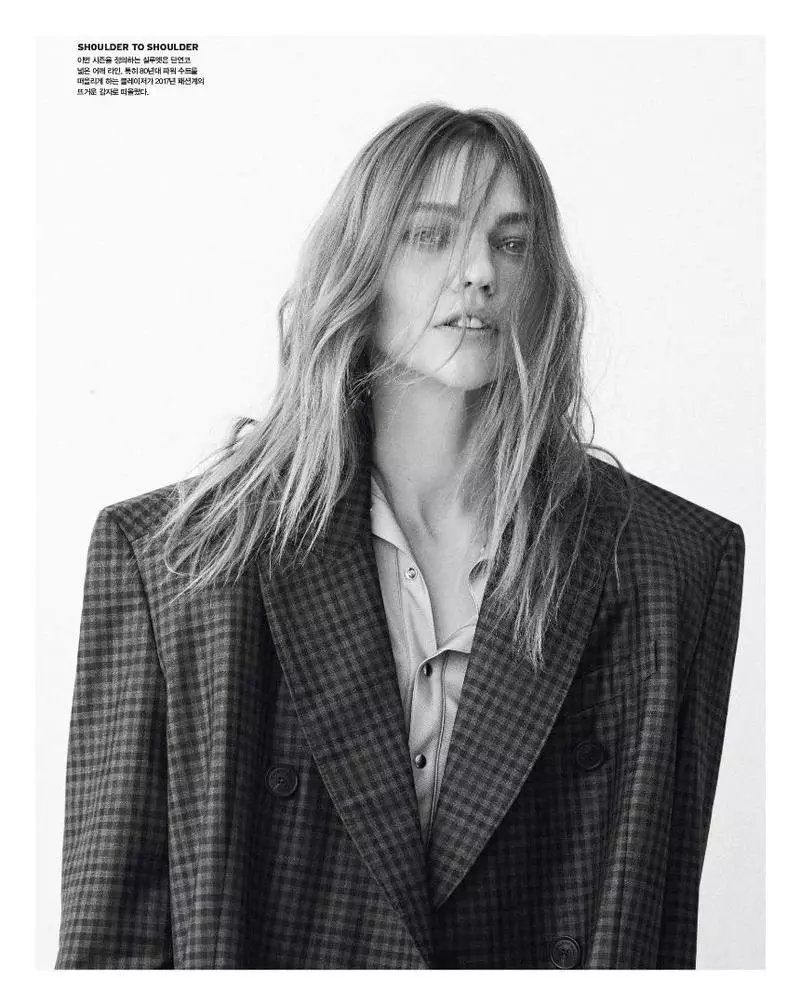 Photographiée en noir et blanc, Sasha Pivovarova porte un manteau à carreaux et une chemise boutonnée Balenciaga