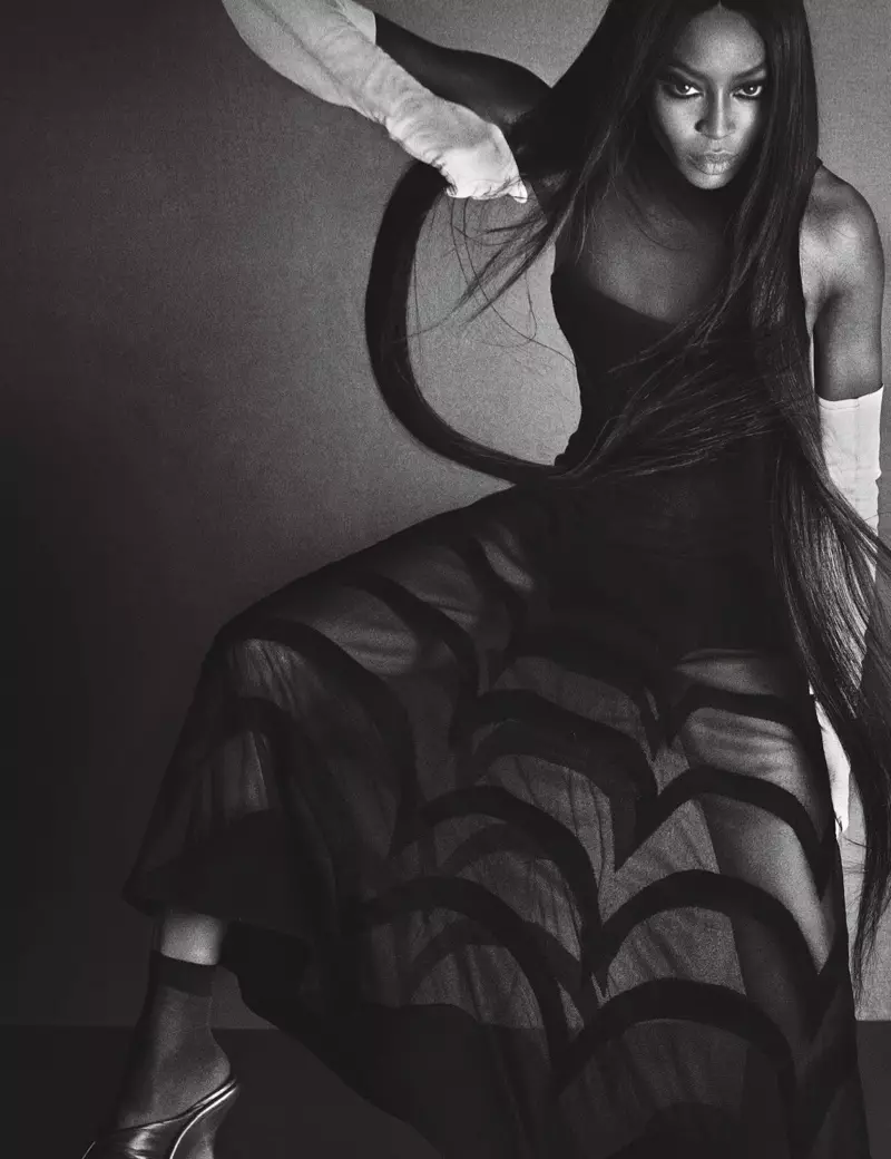 Η Naomi Campbell, με έντονο βλέμμα, φοράει φόρεμα Azzedine Alaïa, γάντια Gaspar και παπούτσια Balenciaga