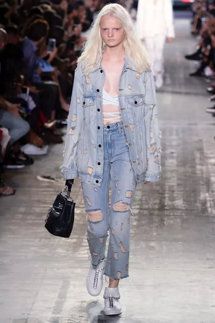 Alexander Wang printemps 2017 : le mannequin défile dans une veste en jean effet vieilli et un jean avec un haut à bretelles