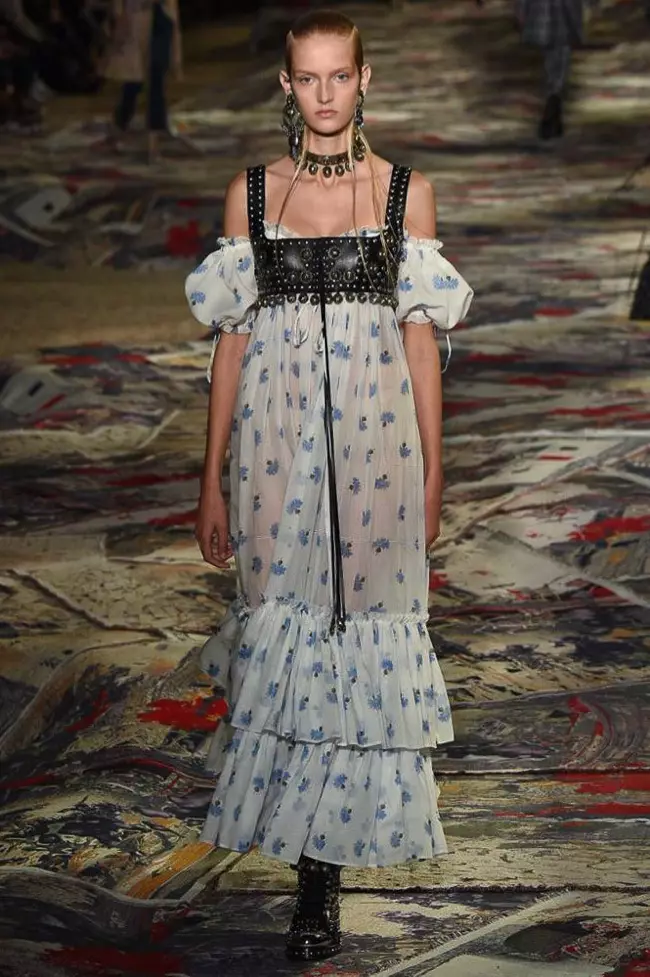 Alexander McQueen primavera 2017: modelo camina por la pasarela con un bustier de cuero sobre un vestido con hombros descubiertos