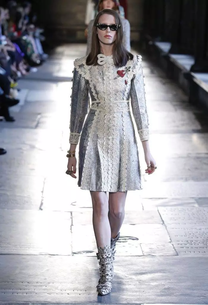 Usa ka modelo ang naglakaw sa runway sa Gucci's resort 2017 show nga nagsul-ob og lace-embellished nga sinina nga adunay pana sa neckline