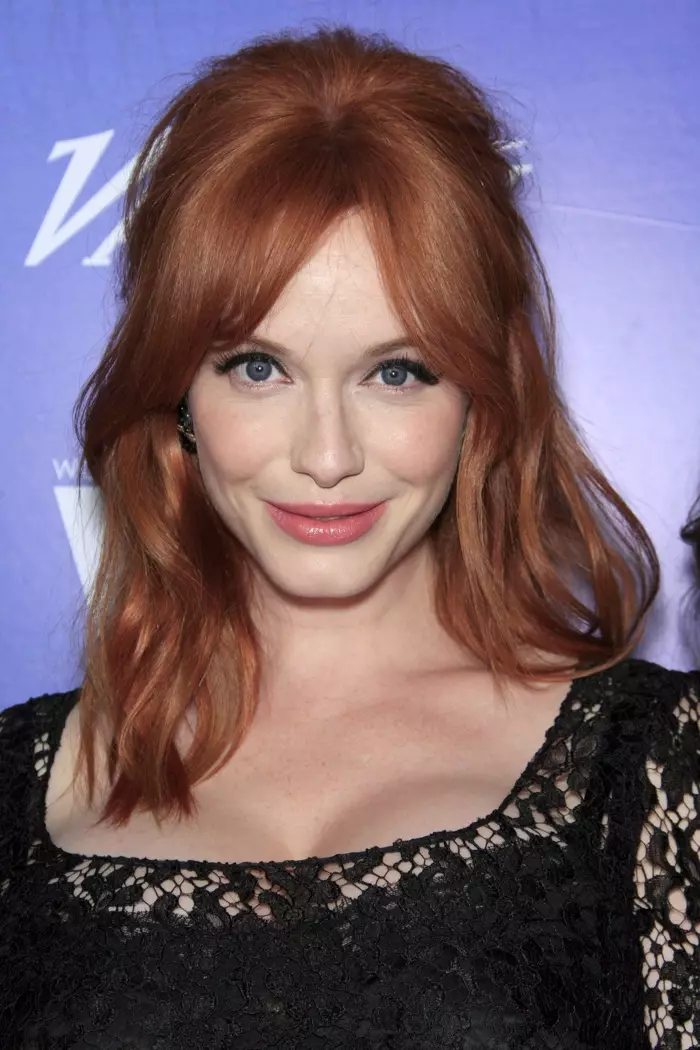 Christina Hendricks flokëkuqe mban flokë me onde gjysmë lart, gjysmë poshtë për flokë me gjatësi mesatare me balluke të ndara. Foto: Helga Esteb / Shutterstock.com