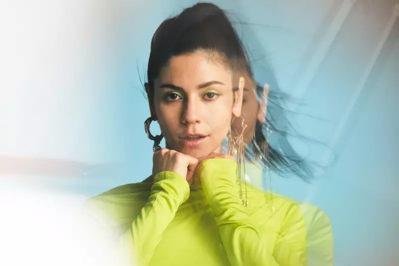 Marina Diamandis, sportief in neongroen, poseer in Versace-rok met Givenchy-oorbelle