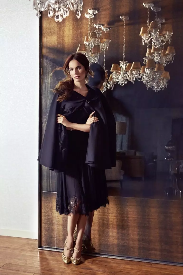 Camilla Belle, gekleed in een cape en zwarte kanten jurk, poseert in een chique look