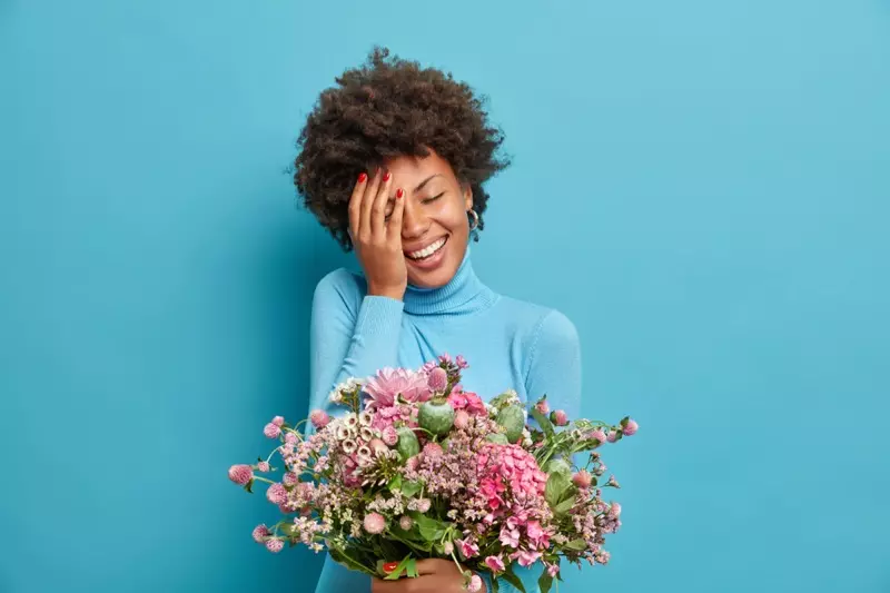 Mosolygó afro modell kezében virágcsokor ajándék