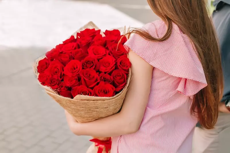 Nő kezében egy csokor vörös rózsa