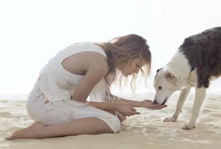 Vanessa Paradis, geklee in wit, poseer saam met 'n hond in hierdie skoot