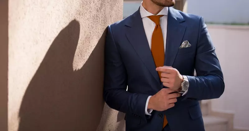 Vyriško modelio mėlynas kostiumas, oranžinis kaklaraištis